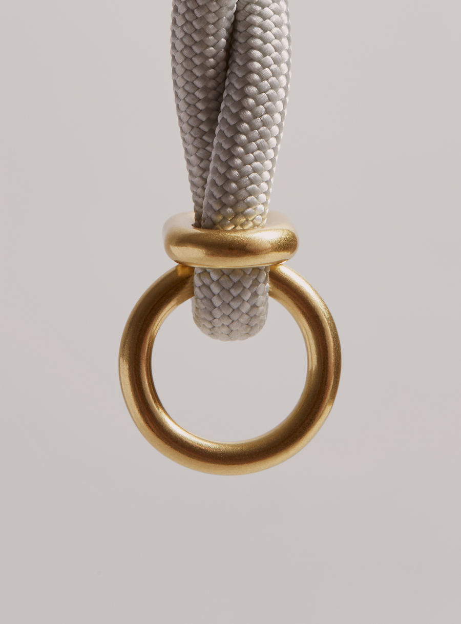 Close up of MANTLE® dog system lead in Haze with solid brass hardware, focus on the brass connection ring on a light gray background