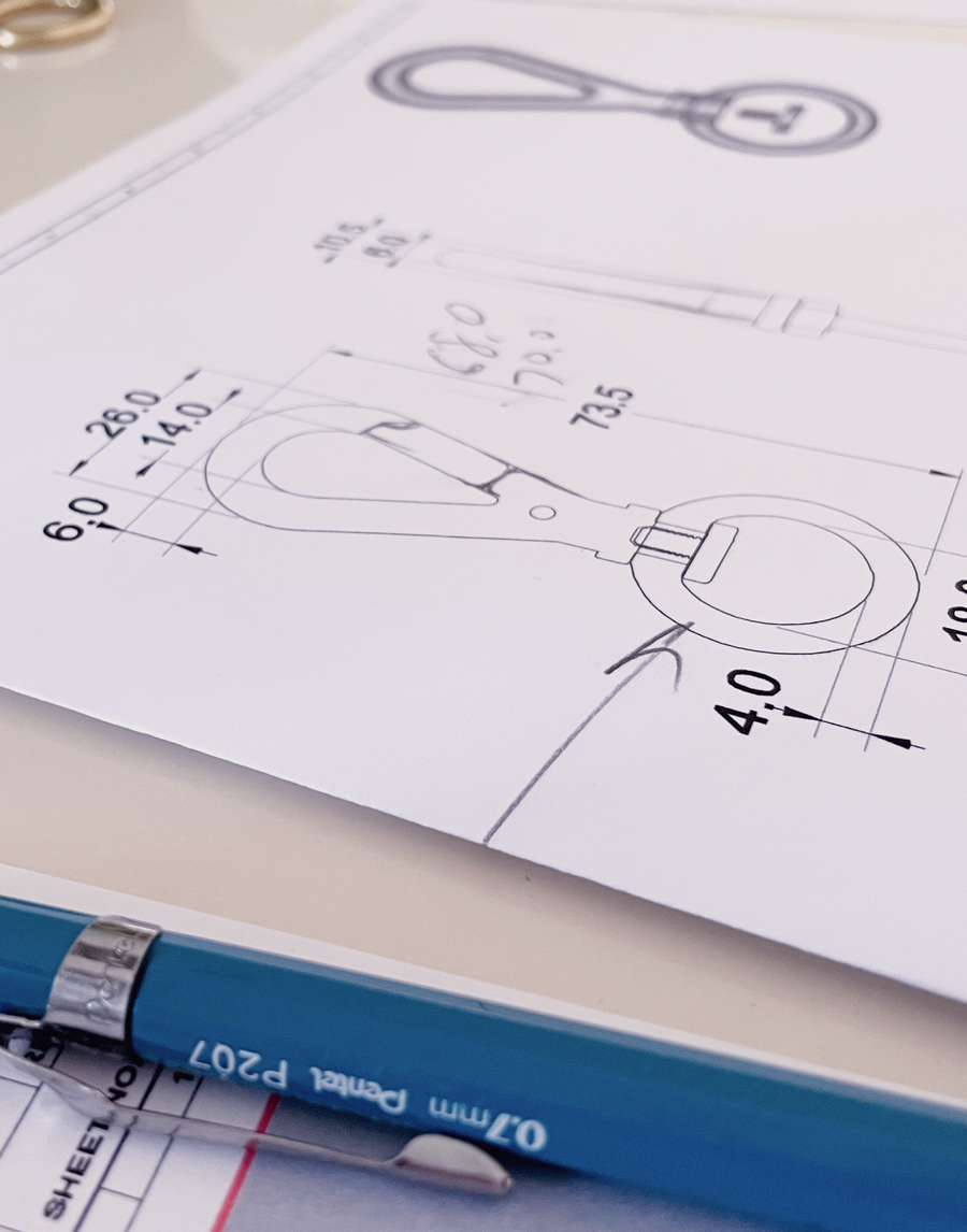 Close up view of the MANTLE® custom connection clip prototype technical drawings with blue pen on a white table
