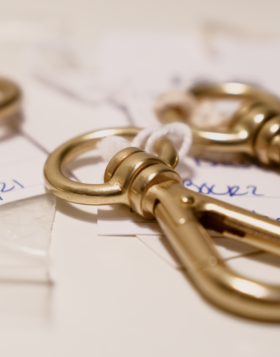 Close up view of the MANTLE® custom connection clip prototypes shown solid brass scattered on a white table
