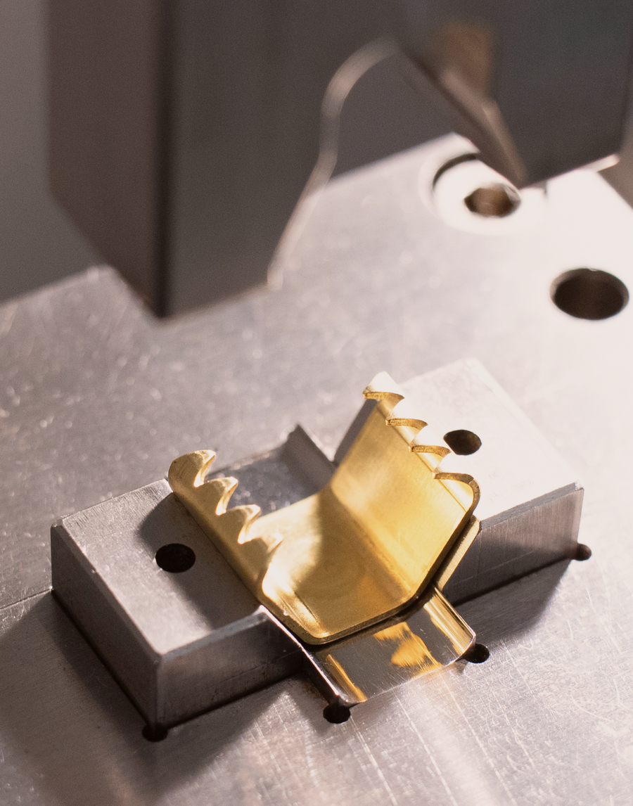 Close up view of tooling that applies the MANTLE branded connection clamp onto the Cording